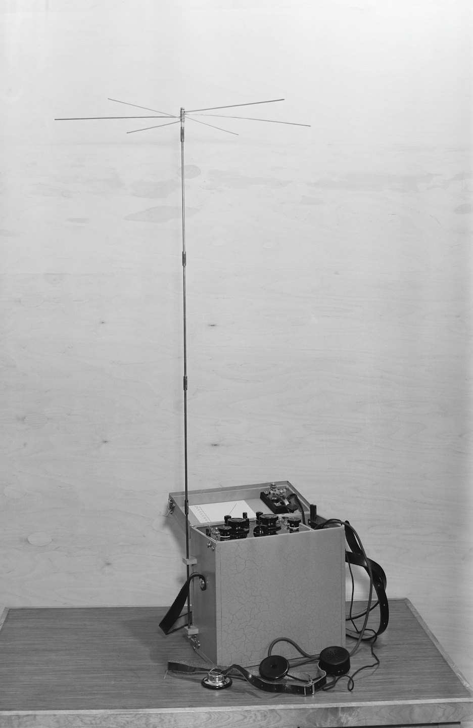 Na drewnianym stole leży zabytkowy radiotelefon z kluczem telegraficznym.