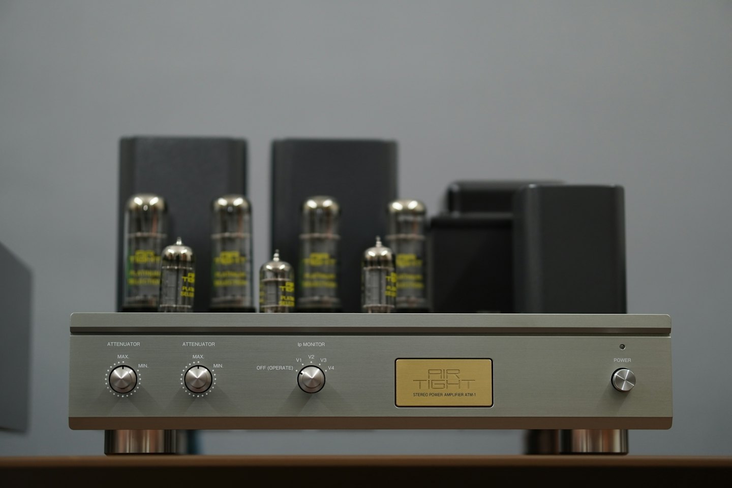 Wzmacniacz stereo z lampami elektronowymi i świecącymi bańkami na drewnianej powierzchni.