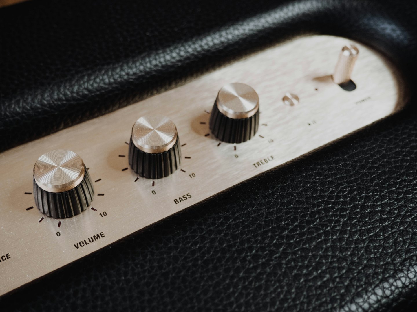 Trzy metalowe pokrętła i włącznik zasilania na sprzęcie audio.